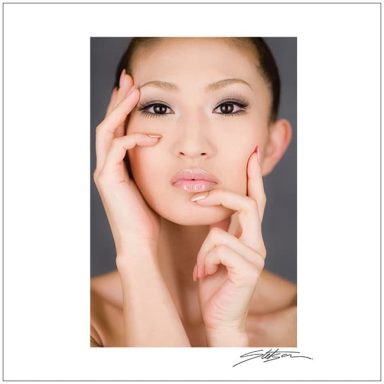 A portrait of a woman with elegant makeup, gently touching her face.