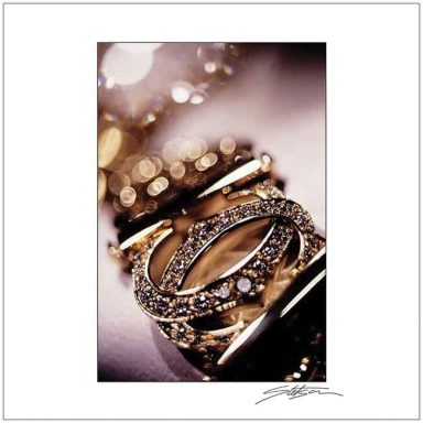 Close-up of intertwined gold and diamond rings against a soft blurred background.