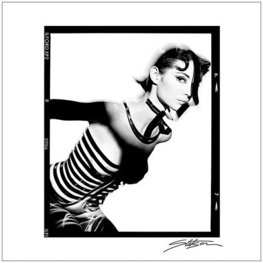 A black-and-white portrait of a woman in a striped top, striking a bold pose.