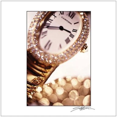 Gold watch with a sparkling bezel and Roman numerals on a blurred, light background.